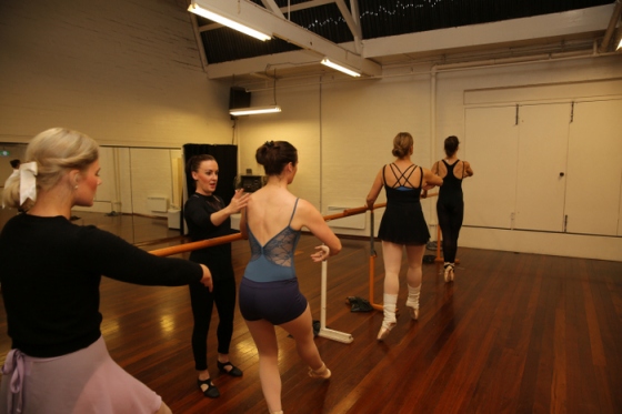 Adult ballerinas in a pointe class with the teacher providing corrections. 